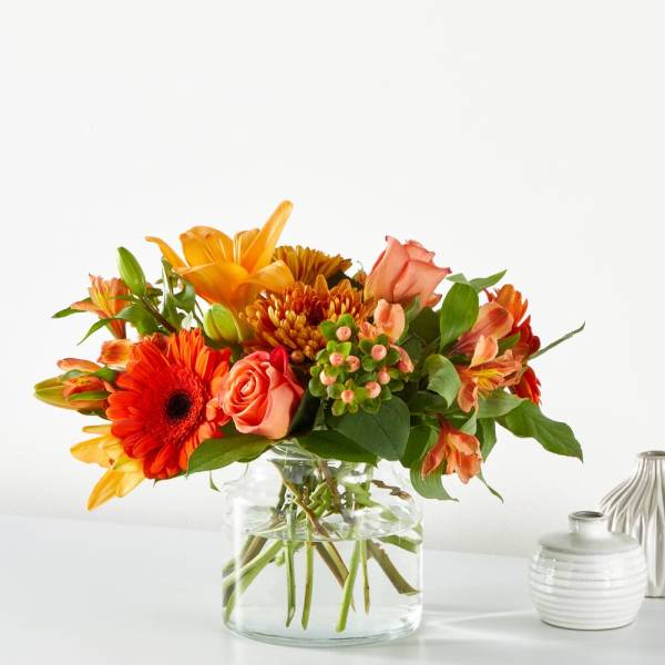 Orange and peach mixed bouquet in a clear glass vase