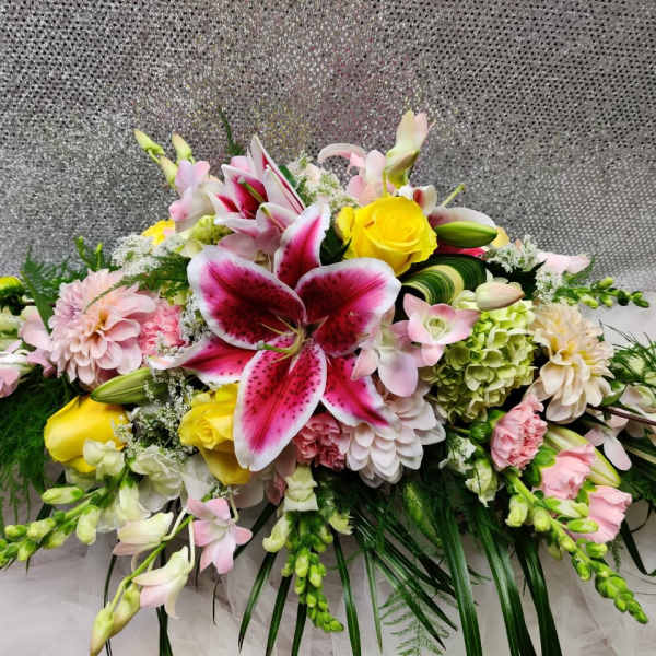 Large floral arrangement with pink lilies, yellow roses, and pastel blooms
