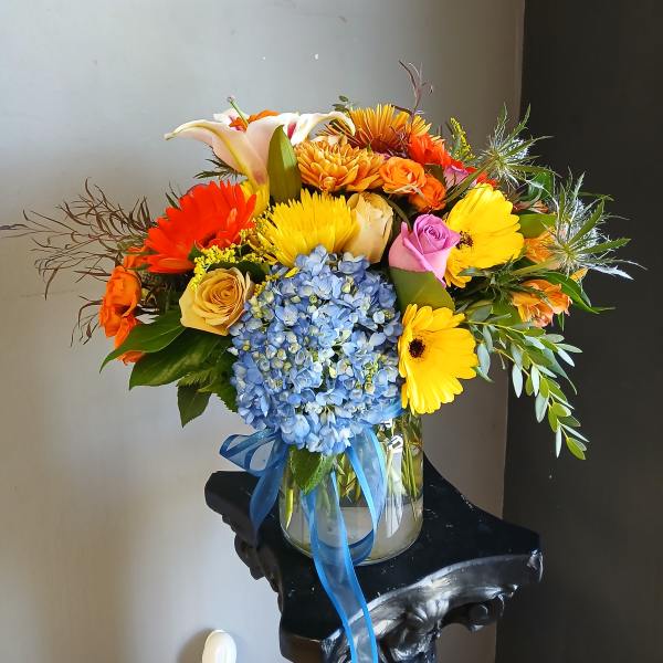 Colorful mixed bouquet in a glass vase with blue ribbon