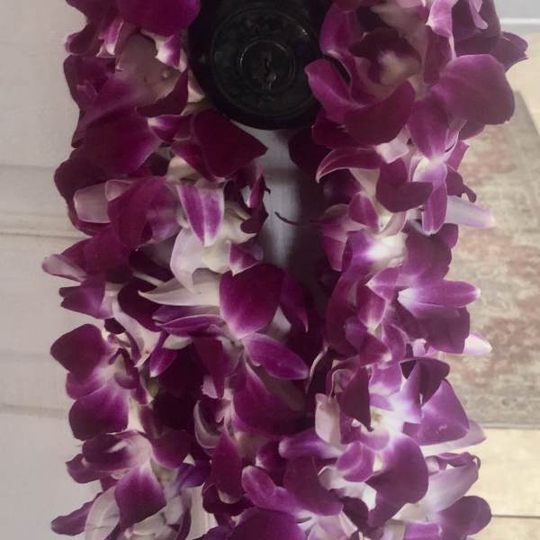 Purple orchid lei draped over a dark doorknob