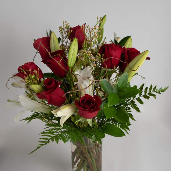 Red roses and white lilies arranged in a clear glass vase