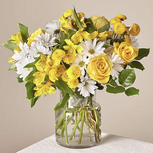 Yellow roses and white daisies in a clear glass vase