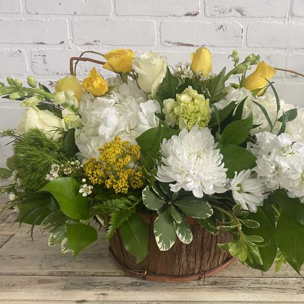 Yellow and white floral arrangement in a rustic wooden basket