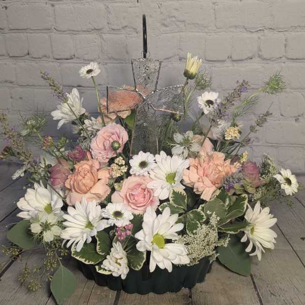 Pastel floral arrangement with daisies, roses, and a glass cross