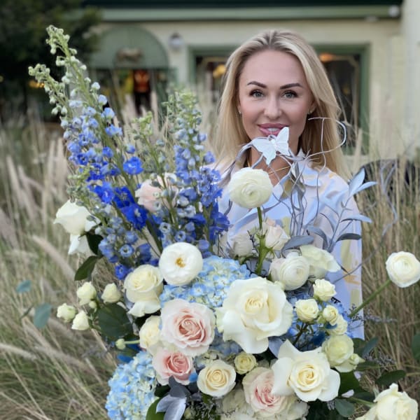 Woman holding a large bouquet of white, pink, and blue flowers in a box