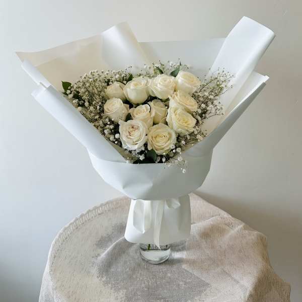 Bouquet of cream roses with baby's breath in white wrapping