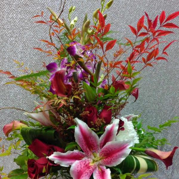Tall bouquet of pink lilies, red roses, and purple orchids