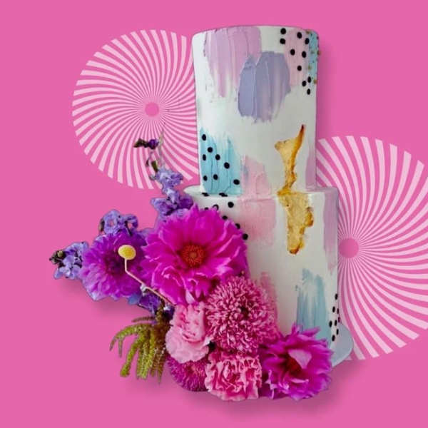 Pink floral arrangement beside a painted two-tier cake