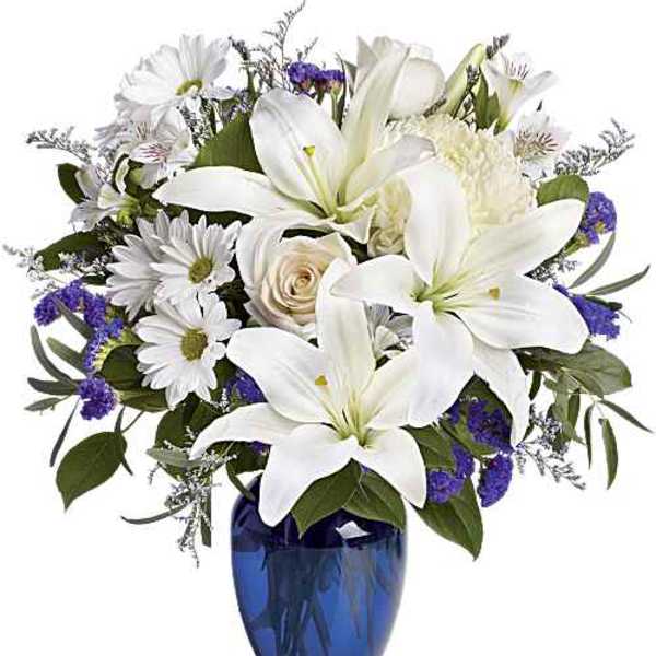 White lilies and daisies in a blue glass vase