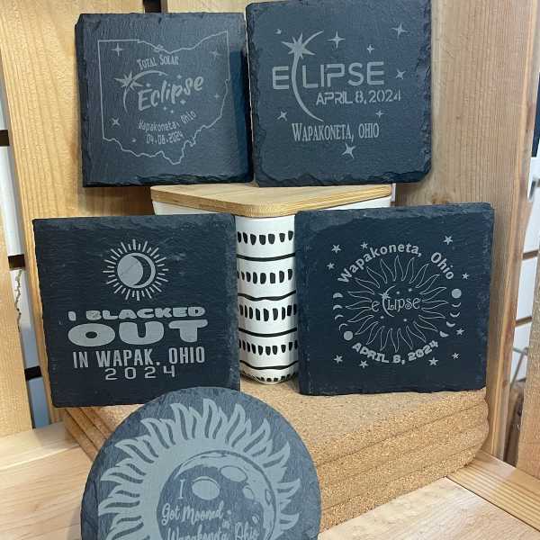 Decorative slate coasters with eclipse-themed designs and a small patterned container