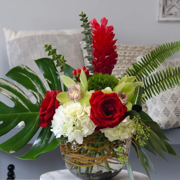 Tropical floral arrangement with red roses and white hydrangeas in a glass vase