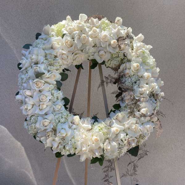 Large white floral wreath on a wooden easel