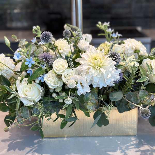 White roses and dahlias in a gold rectangular vase with blue accents