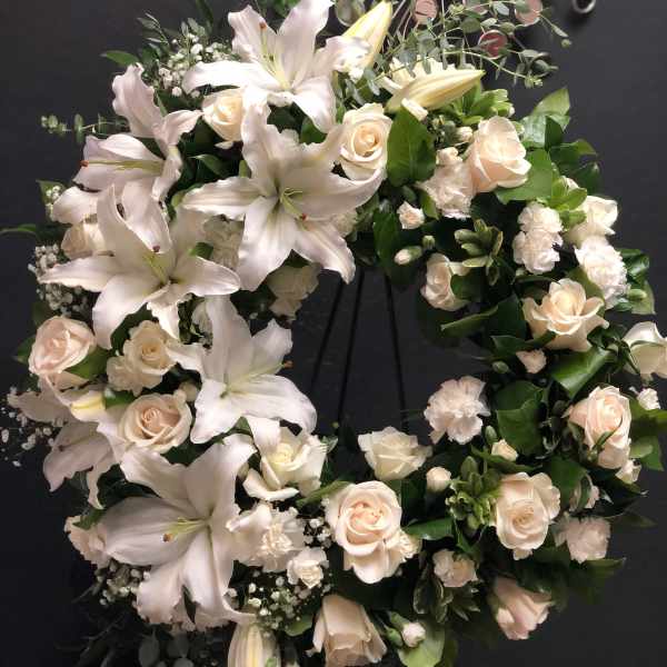 White lily and rose wreath on a dark stand