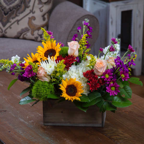 Mixed bouquet with sunflowers, roses, and chrysanthemums in a wooden box