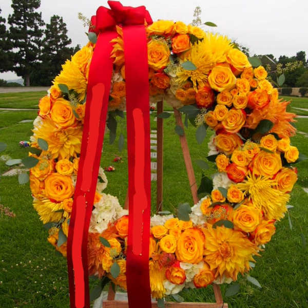Large floral wreath of yellow and orange roses with a red ribbon