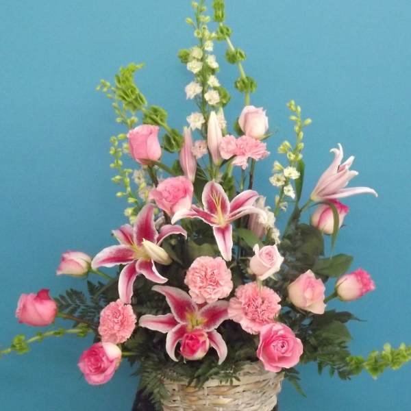 Pink roses, lilies, and carnations arranged in a basket