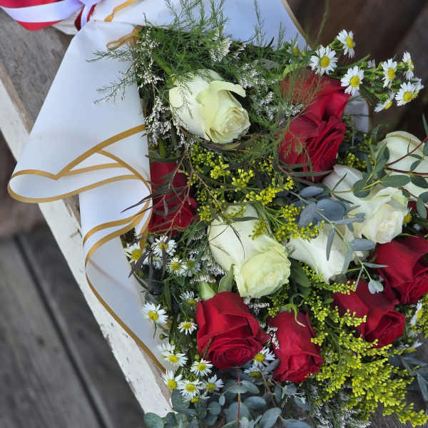 Bouquet of red and white roses with small daisies in white wrap