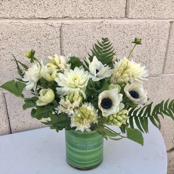 White flowers arranged in a green glass vase