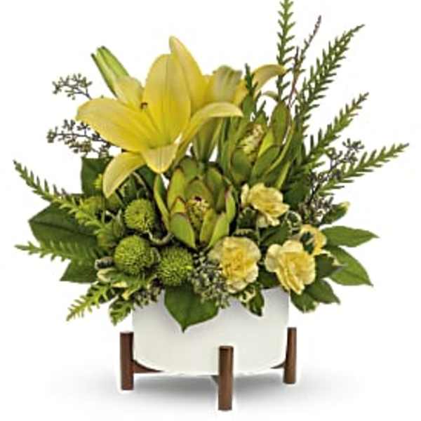 Yellow lilies and green flowers in a white container on wooden legs