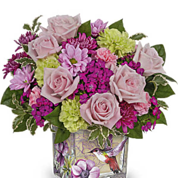 Pink roses and mixed blooms arranged in a square glass vase