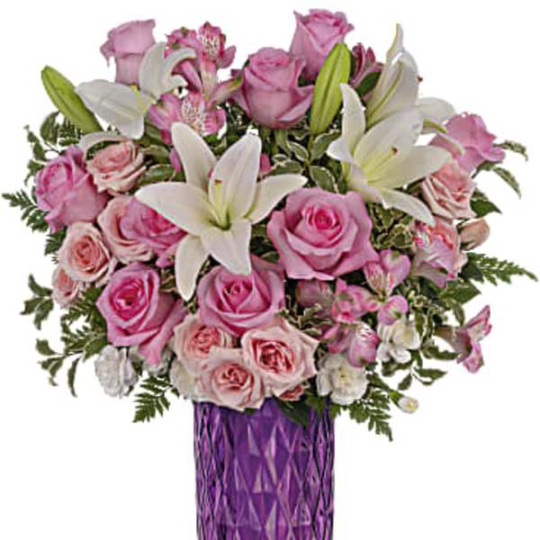 Pink roses and white lilies arranged in a purple vase