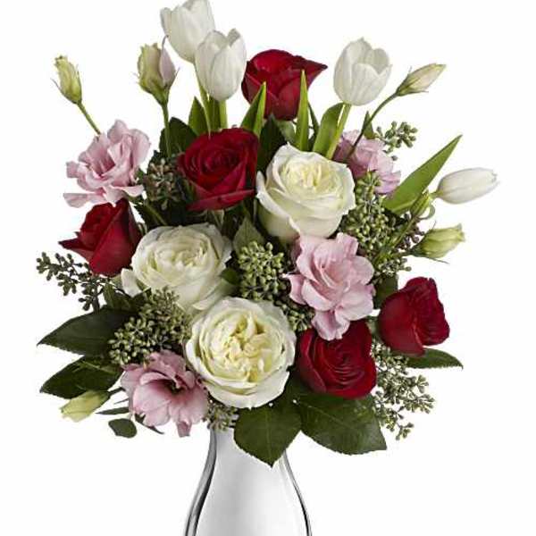 Bouquet of red, white, and pink roses in a clear glass vase
