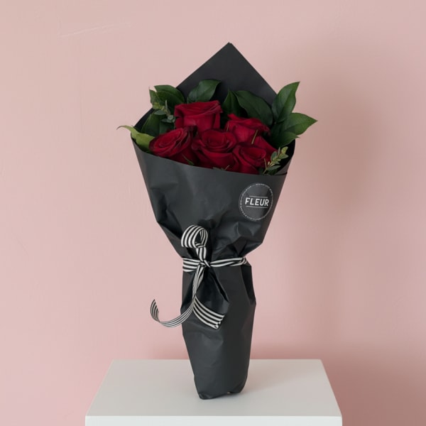 Bouquet of red roses wrapped in black paper with a striped ribbon