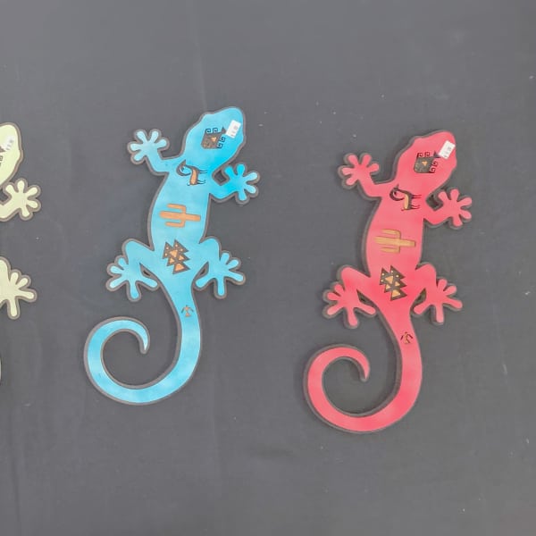 Four colorful gecko-shaped cutouts on a dark background