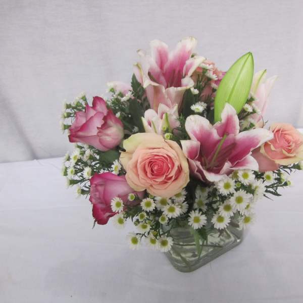 Pink roses and lilies arranged in a clear glass vase