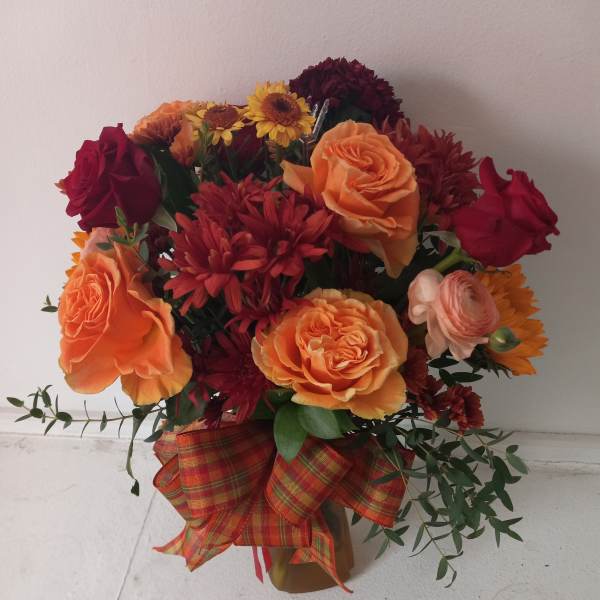 Bouquet of orange and red flowers with a plaid ribbon
