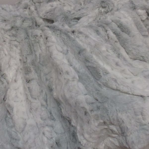 Close-up of a light gray faux fur fabric with a shaggy texture.