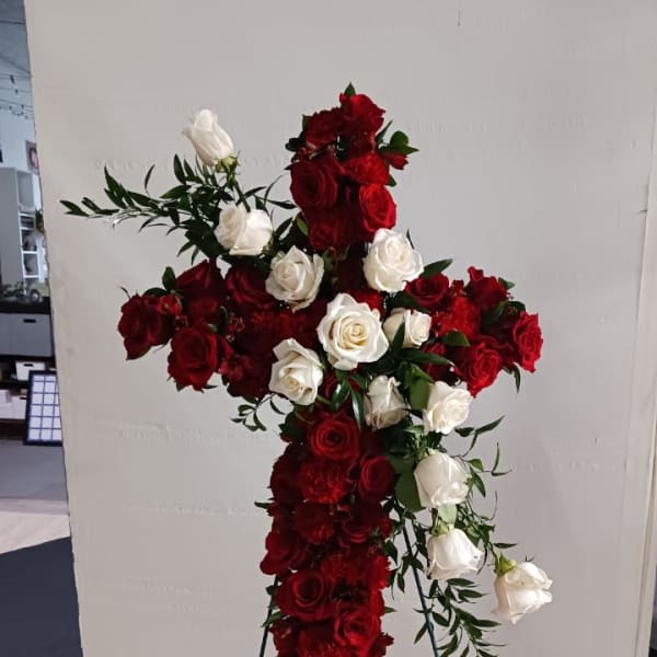Cross-shaped floral arrangement of red and white roses on a stand