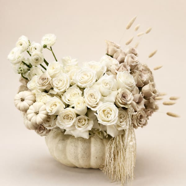Cream rose arrangement in a white pumpkin container with dried accents