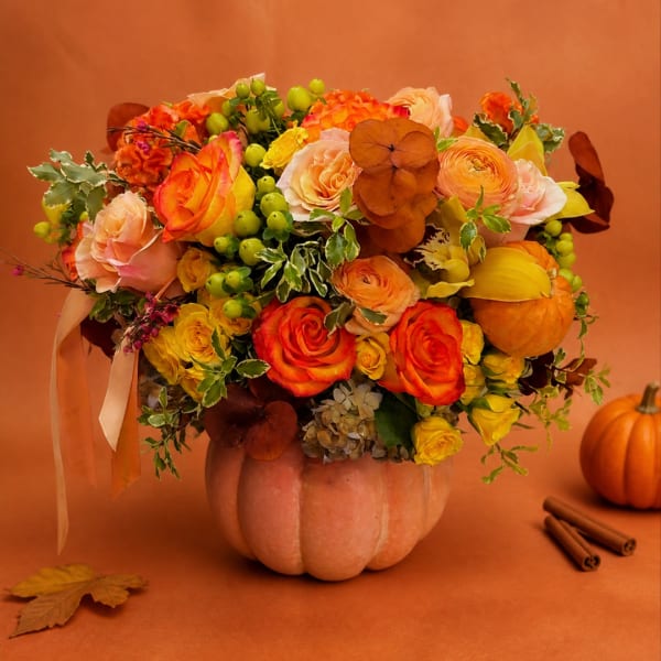 Autumn bouquet of orange and yellow roses in a pumpkin vase