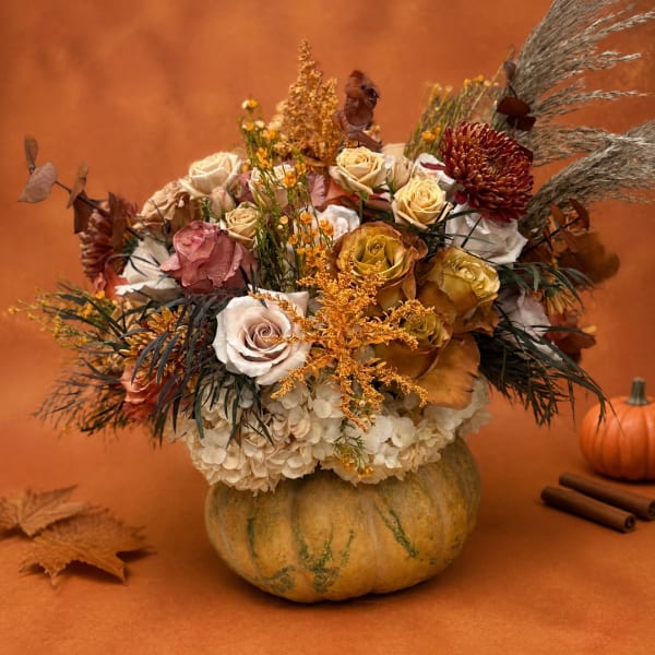 Autumn floral arrangement in a pumpkin vase with roses and hydrangeas
