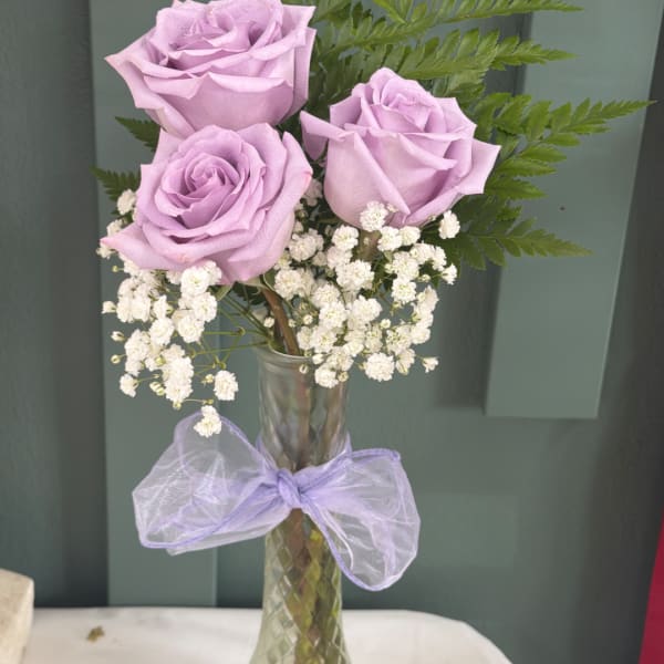 Lavender roses in a clear glass vase with white baby's breath
