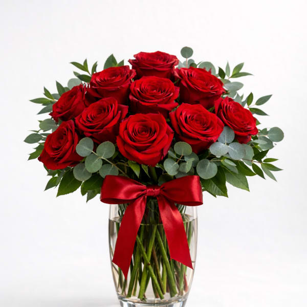 Red roses arranged in a clear glass vase with a red ribbon