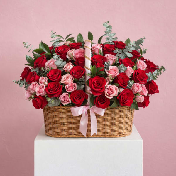 Basket arrangement of red and pink roses with a pink ribbon