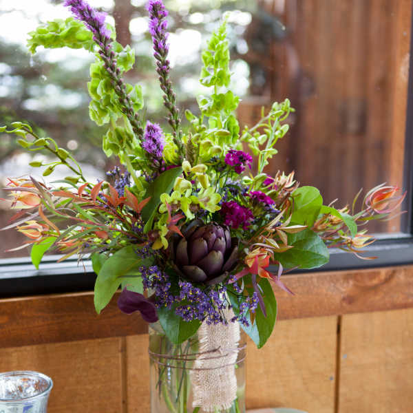 Mixed floral arrangement in a clear glass vase with purple and green blooms