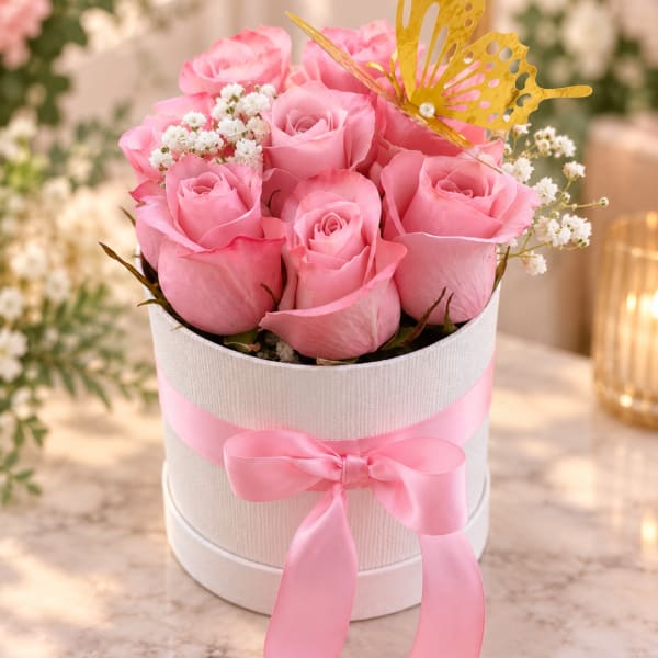 Pink roses in a white hatbox with a ribbon and butterfly topper