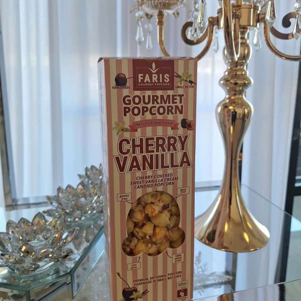Box of cherry vanilla gourmet popcorn beside a gold crystal candelabra