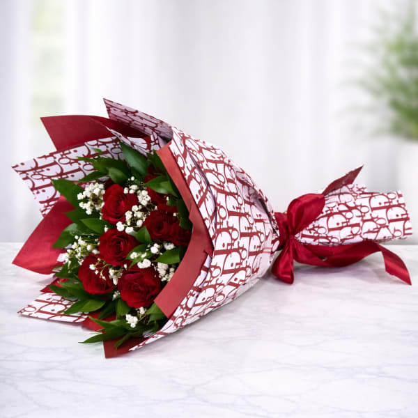 Bouquet of red roses wrapped in patterned paper with a red ribbon