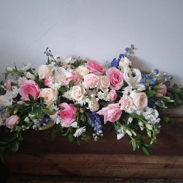 Large pink and white floral casket spray with blue accents