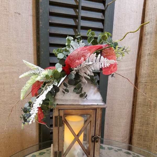 Lantern with greenery and red ribbon on a table