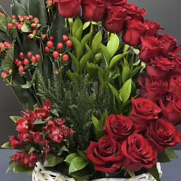 Tall arrangement of red roses with greens in a white woven basket