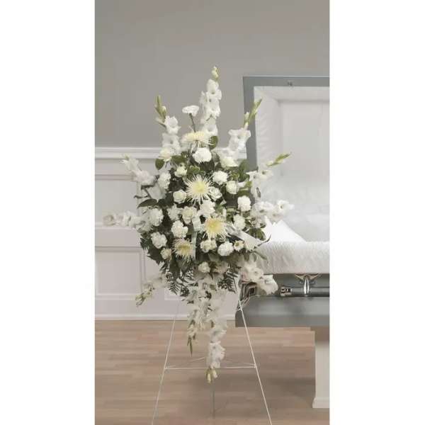 Tall white funeral spray on a stand with cascading flowers