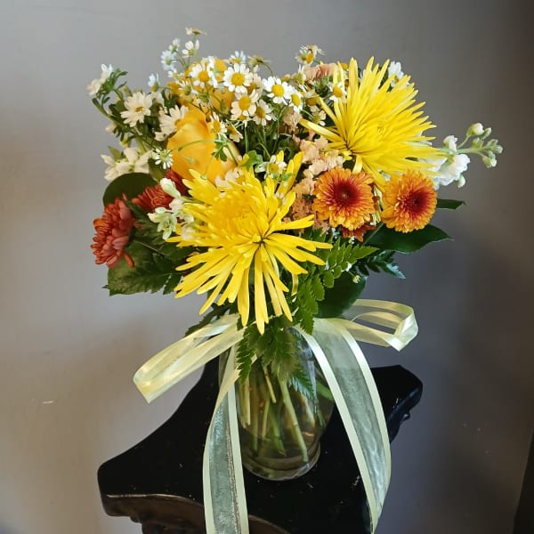 Yellow and orange mixed bouquet in a glass vase with a ribbon