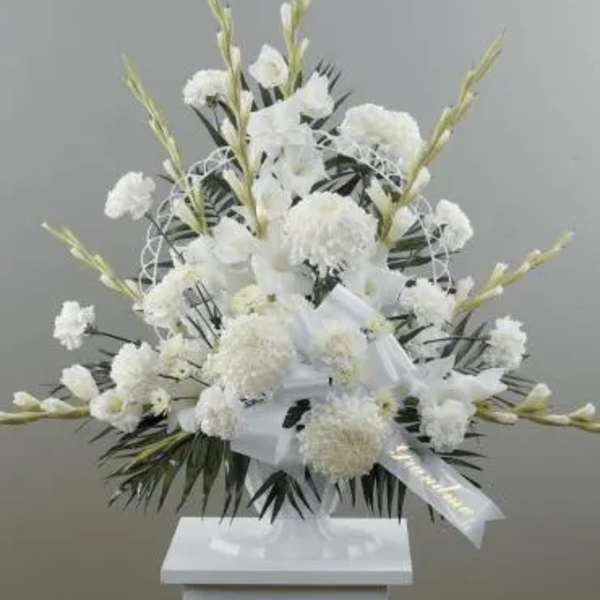 White funeral spray with ribbon on a stand