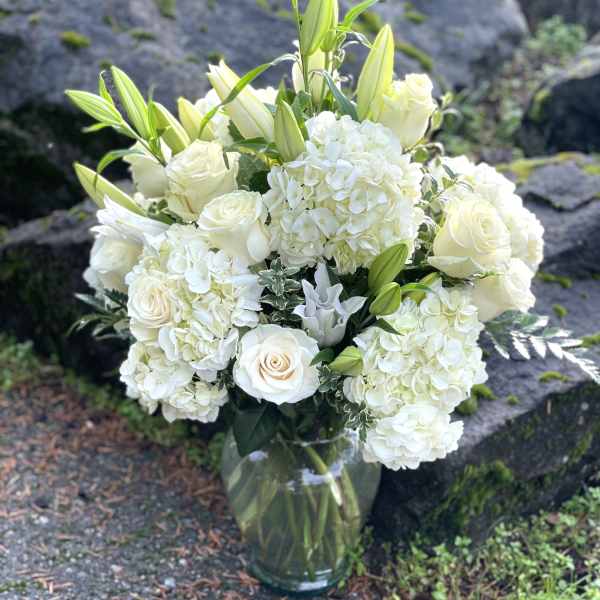 White roses and hydrangeas arranged in a glass vase